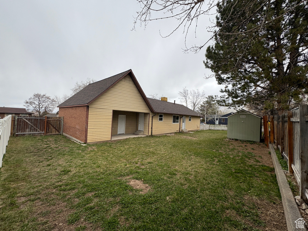 Back of property with a lawn, an outbuilding, a fenced backyard, and a storage shed