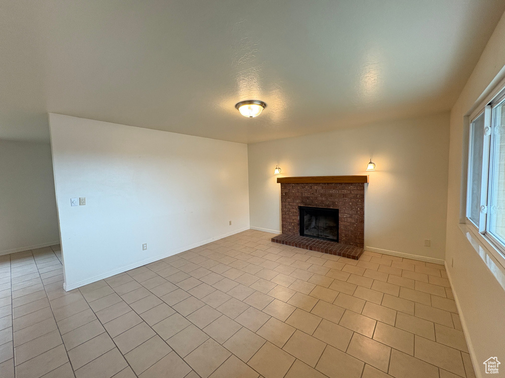 Unfurnished living room featuring baseboards, a fireplace, and light tile patterned floors