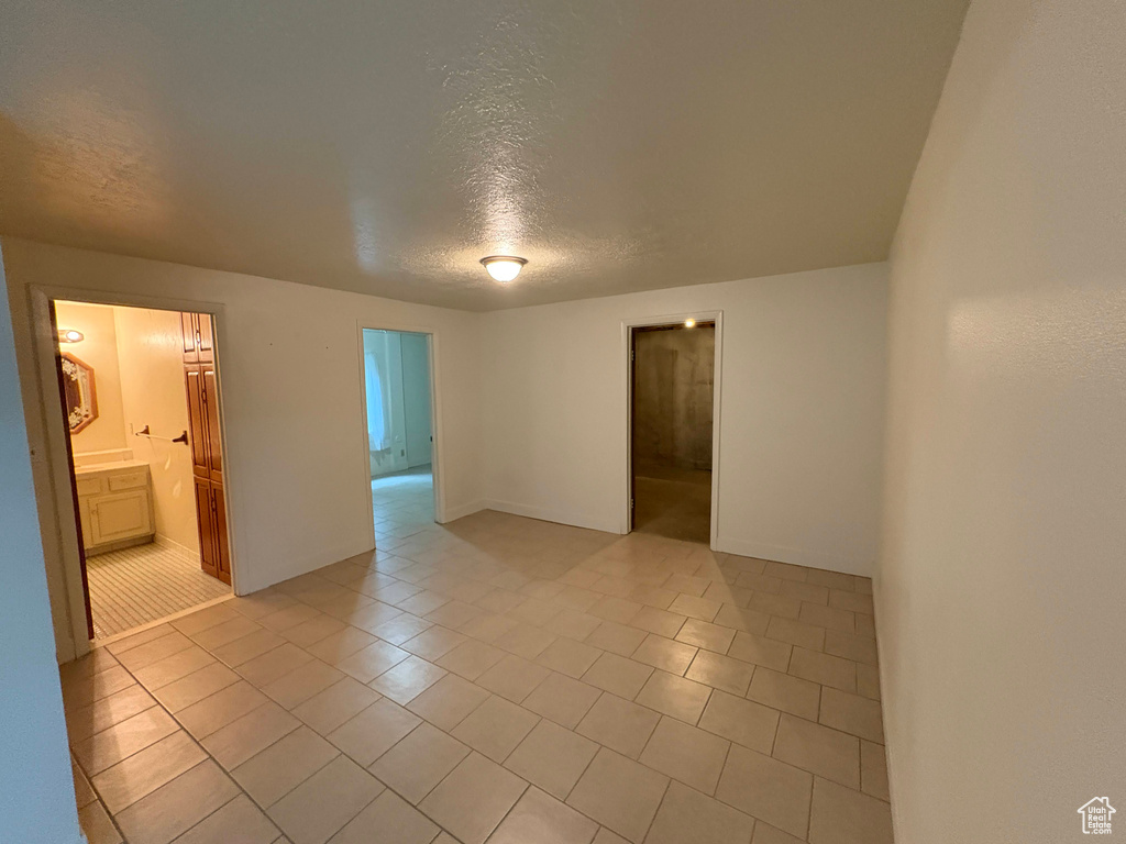 Empty room with light tile patterned flooring and a textured ceiling