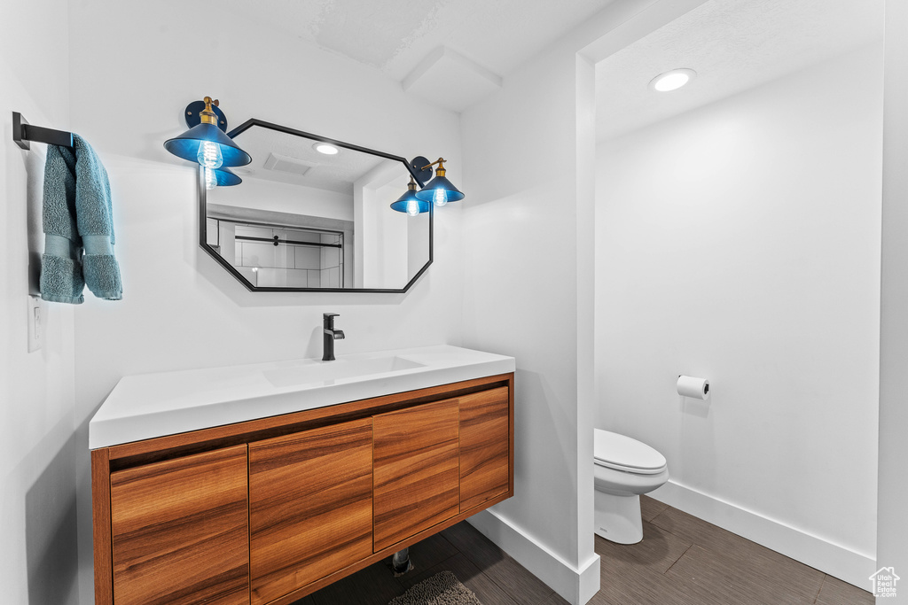 Bathroom featuring toilet, vanity, baseboards, visible vents, and recessed lighting