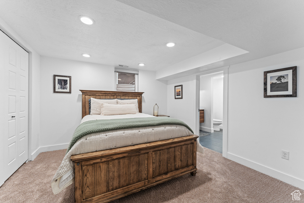 Carpeted bedroom with a textured ceiling, visible vents, baseboards, connected bathroom, and recessed lighting