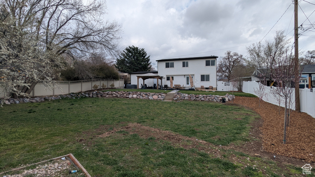 Exterior space with a fenced backyard, a gazebo, a yard, and a patio area