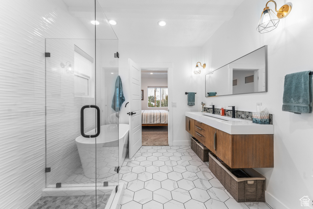 Ensuite bathroom featuring vanity, connected bathroom, a stall shower, and baseboards