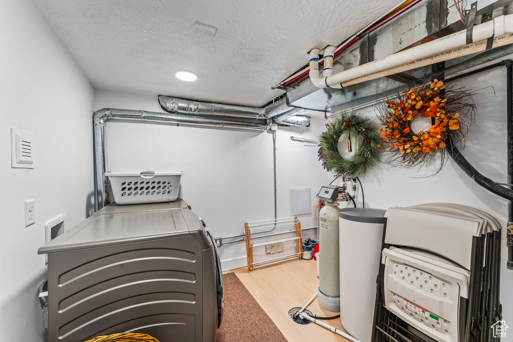 Laundry area featuring washing machine and clothes dryer, wood finished floors, laundry area, and a textured ceiling