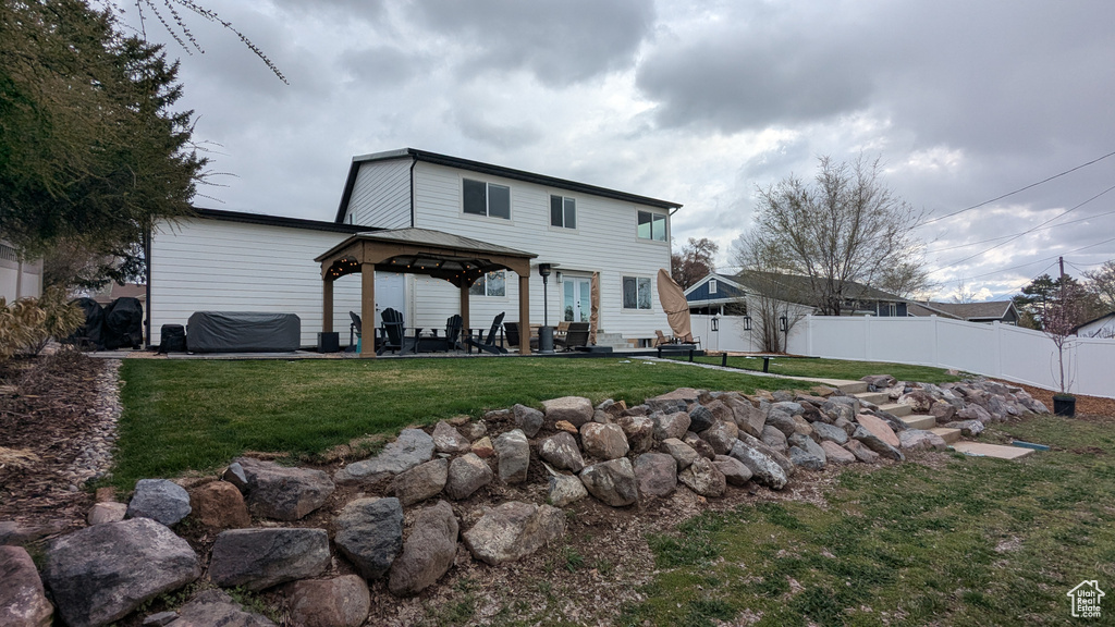 Rear view of house with fence, a lawn, a gazebo, and a patio