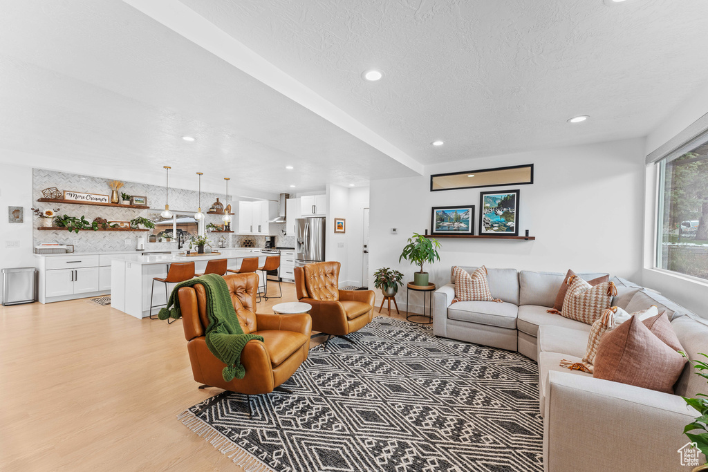 Living area with a textured ceiling, recessed lighting, and light wood finished floors
