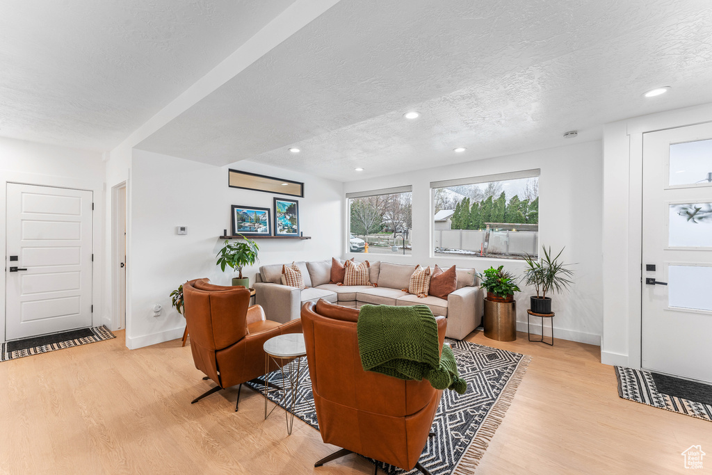 Living room featuring baseboards, a textured ceiling, and light wood finished floors