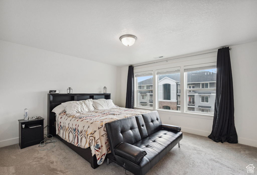 Carpeted bedroom with a textured ceiling, baseboards, and visible vents