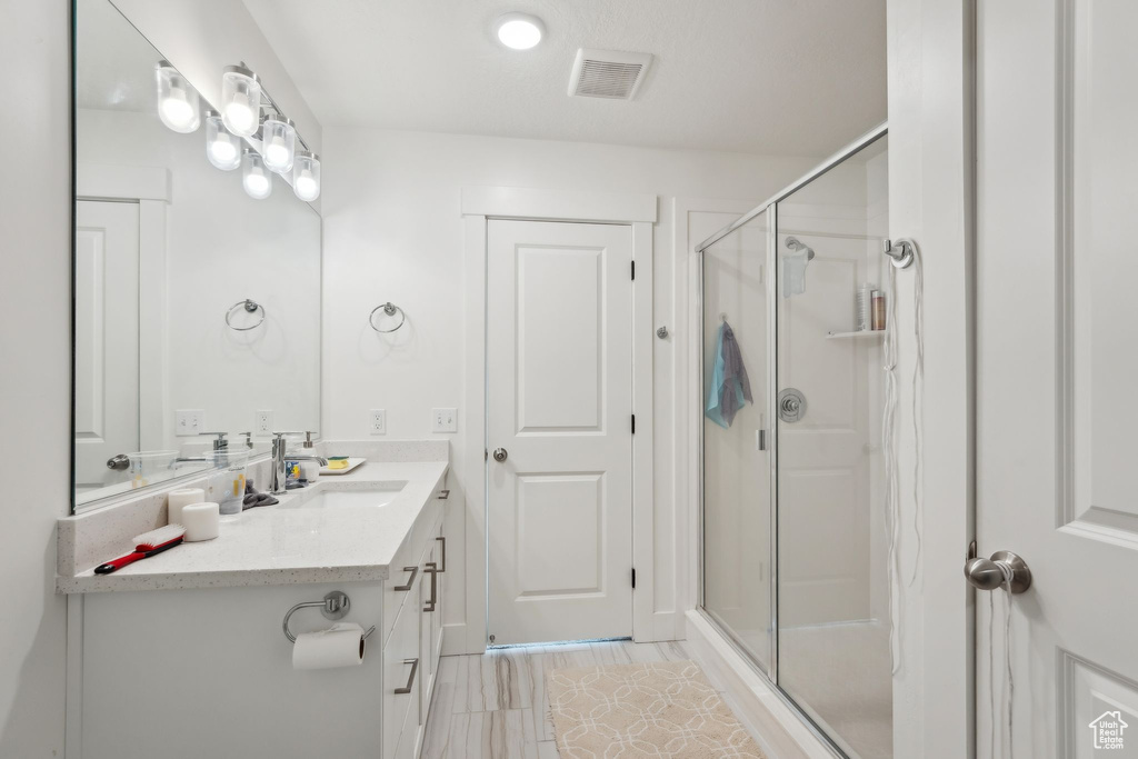 Full bath with a shower stall, visible vents, and vanity