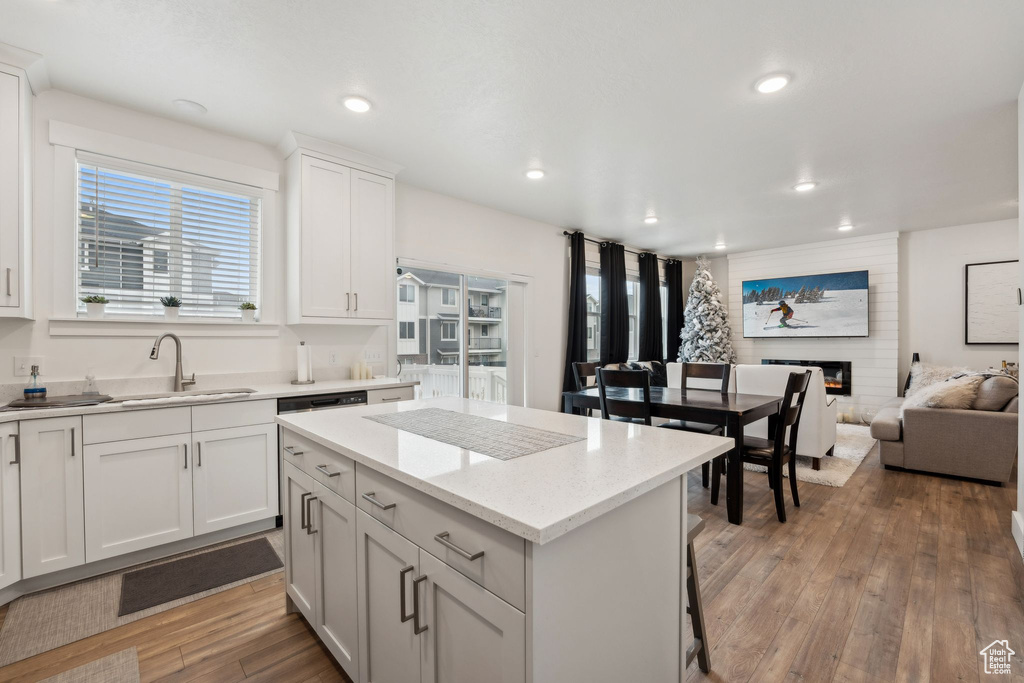 Kitchen with recessed lighting, a center island, a sink, light wood-style flooring, and a fireplace