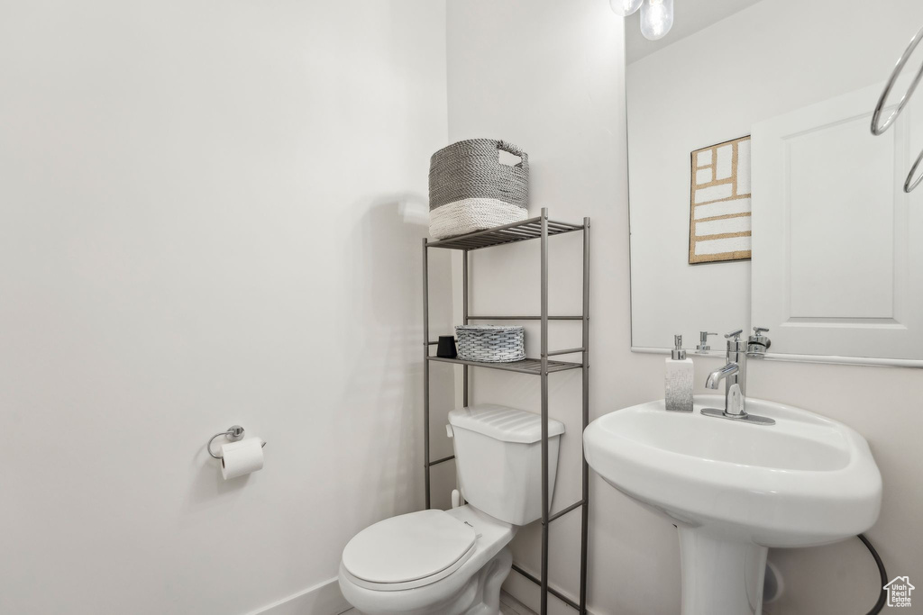 Half bath featuring toilet, a sink, and baseboards