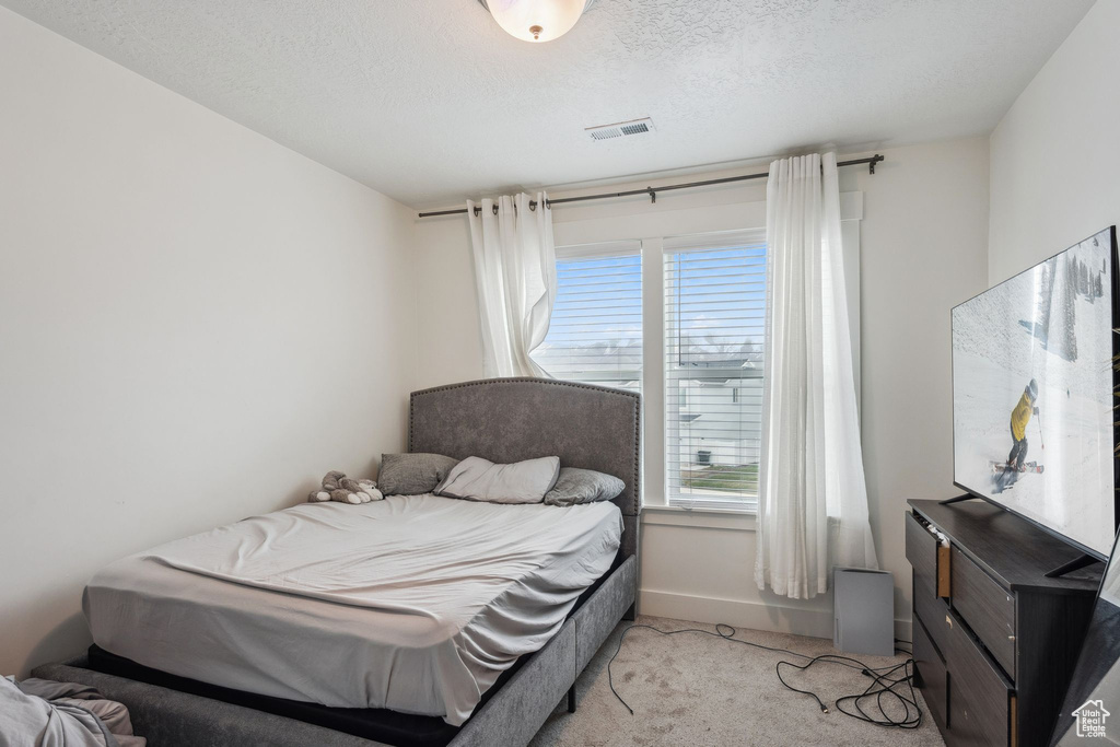 Carpeted bedroom with a textured ceiling, baseboards, and visible vents