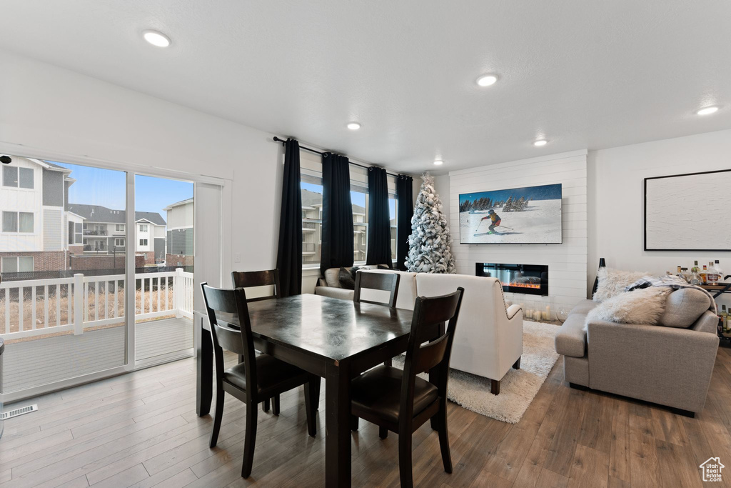 Dining room with recessed lighting, wood finished floors, and a glass covered fireplace
