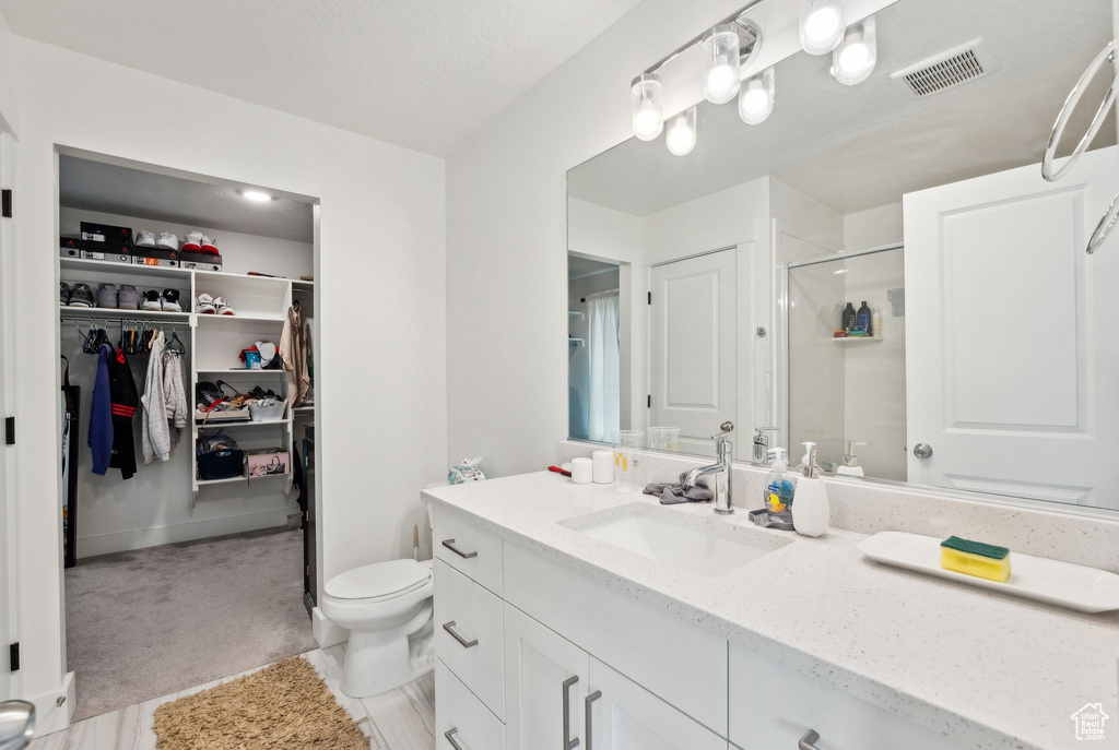 Full bathroom featuring vanity, a spacious closet, toilet, a shower stall, and visible vents