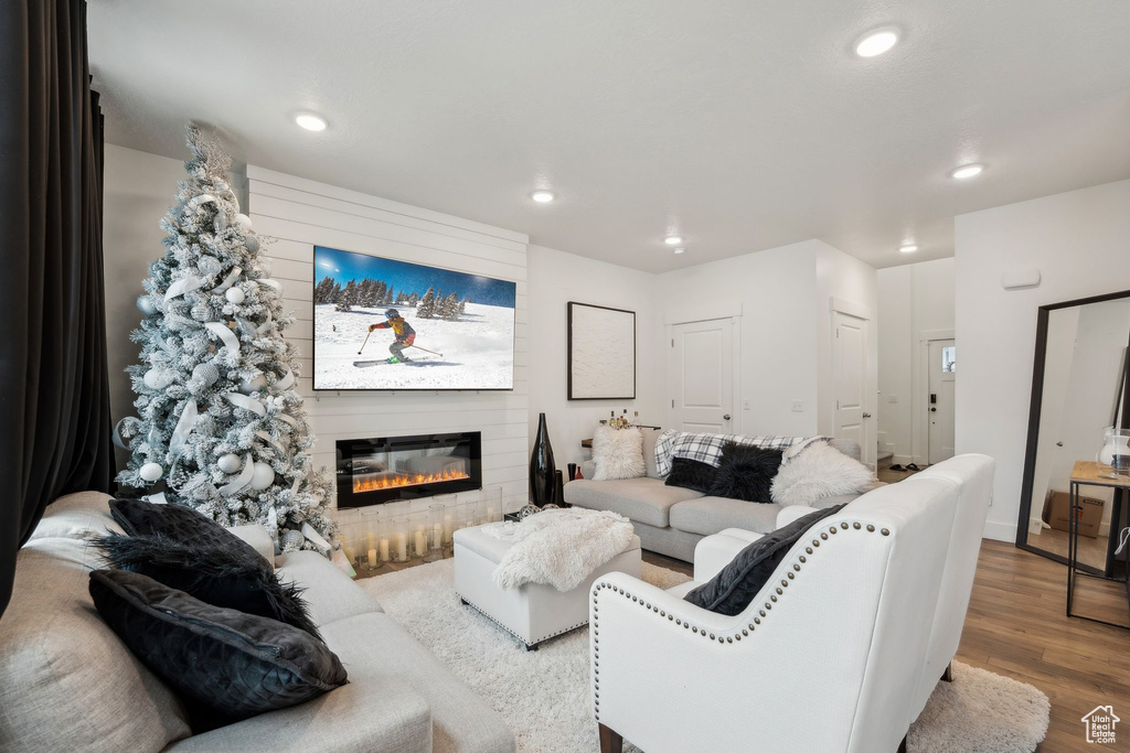 Living area with a large fireplace, recessed lighting, and wood finished floors