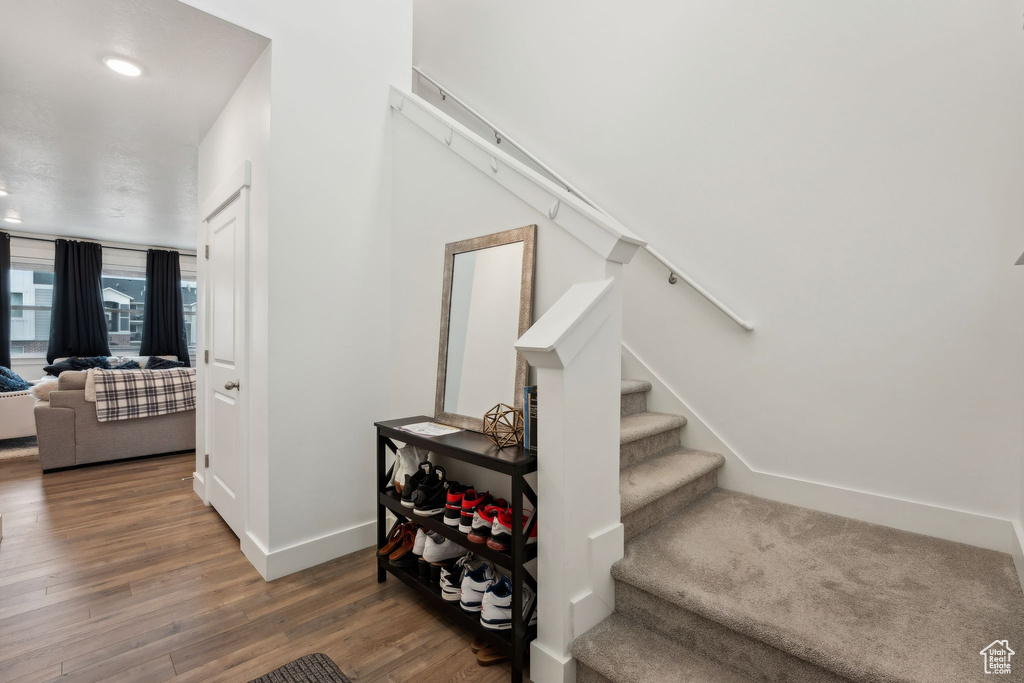 Staircase with baseboards, wood finished floors, and recessed lighting