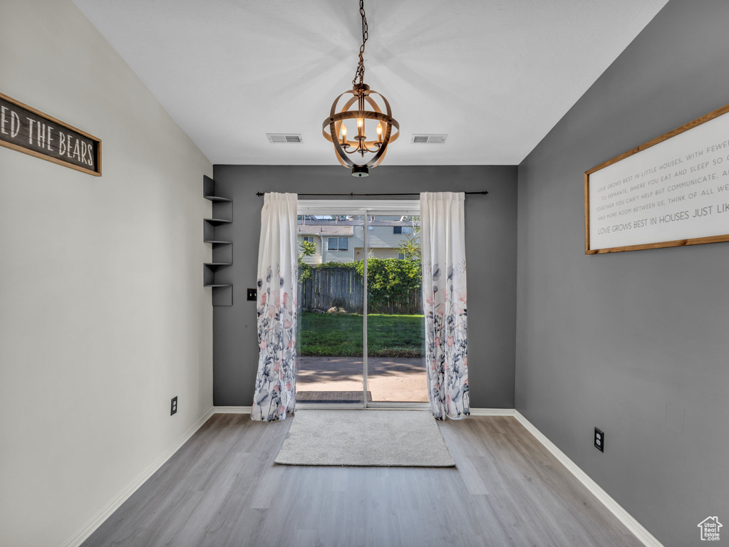 Doorway featuring wood finished floors, a chandelier, and baseboards