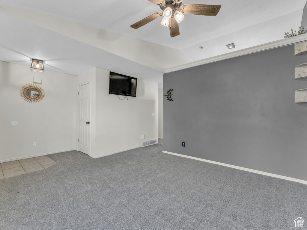 Tiled spare room with carpet flooring, a ceiling fan, and baseboards