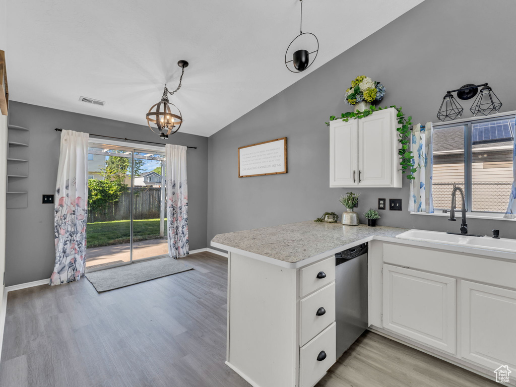 Kitchen with a sink, dishwasher, vaulted ceiling, a peninsula, and white cabinets