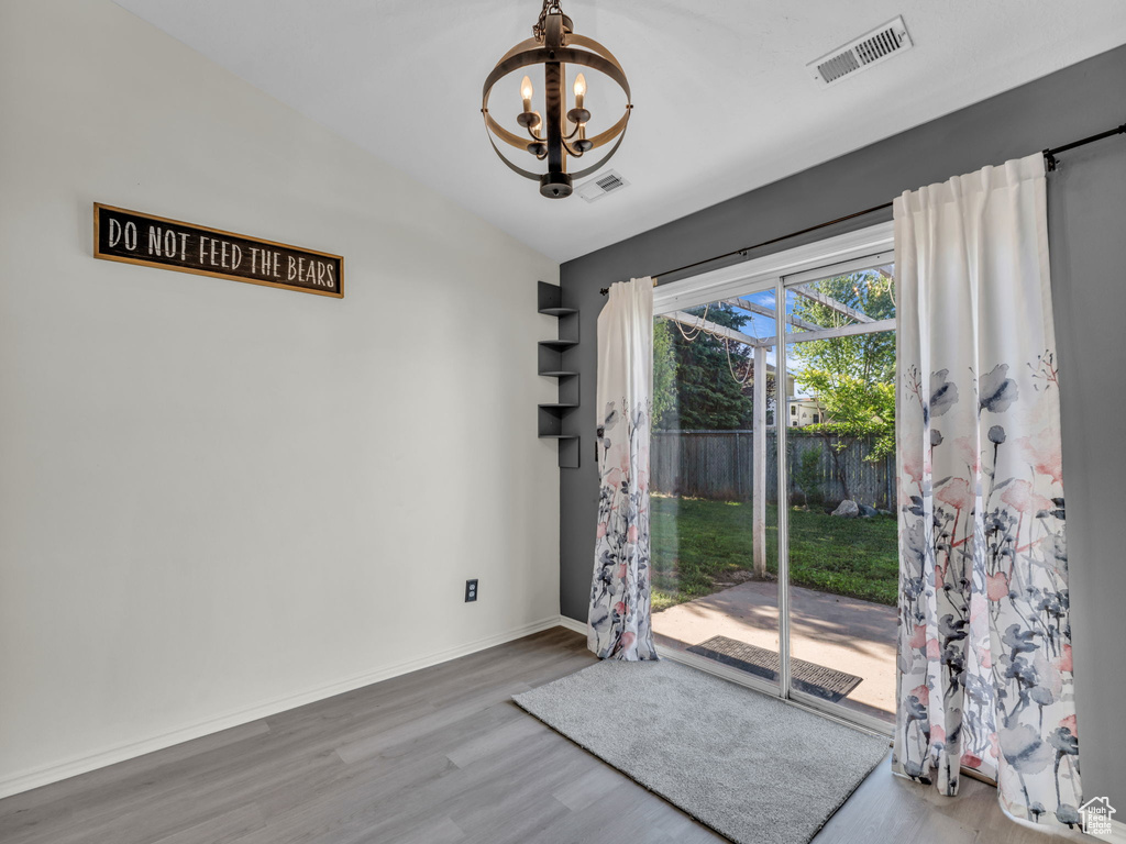 Doorway with a chandelier, wood finished floors, and baseboards