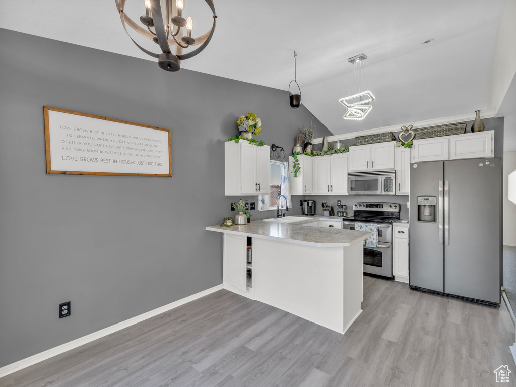 Kitchen featuring appliances with stainless steel finishes, a chandelier, lofted ceiling, a sink, and a peninsula