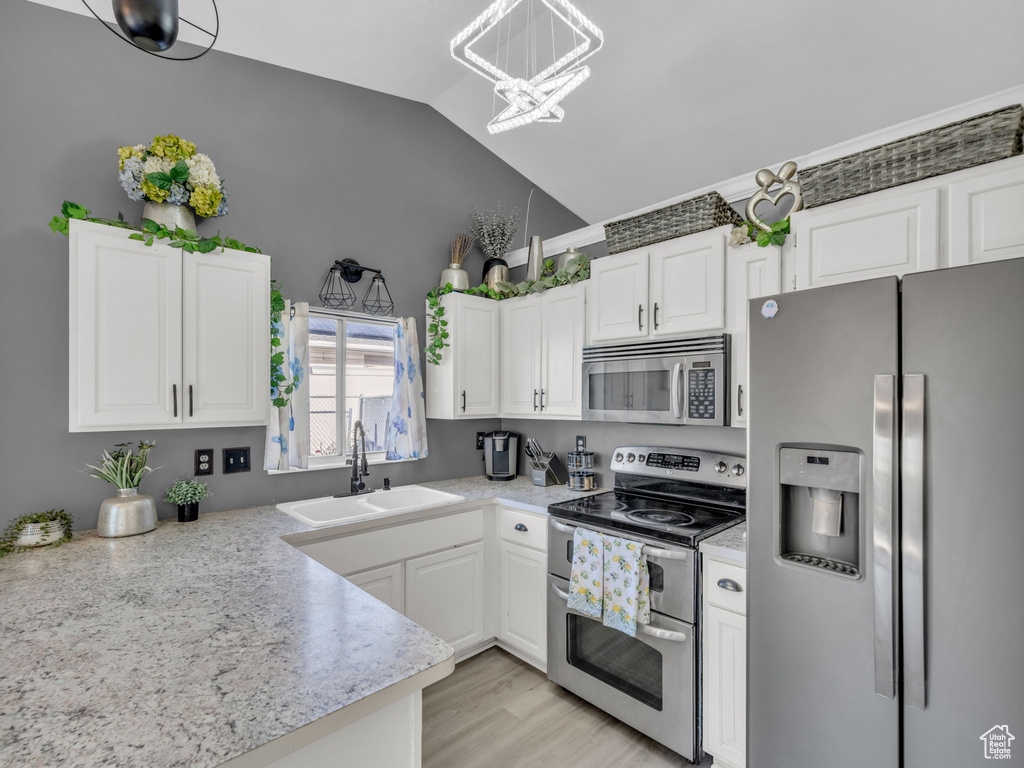 Kitchen with stainless steel appliances, a sink, white cabinetry, and high vaulted ceiling