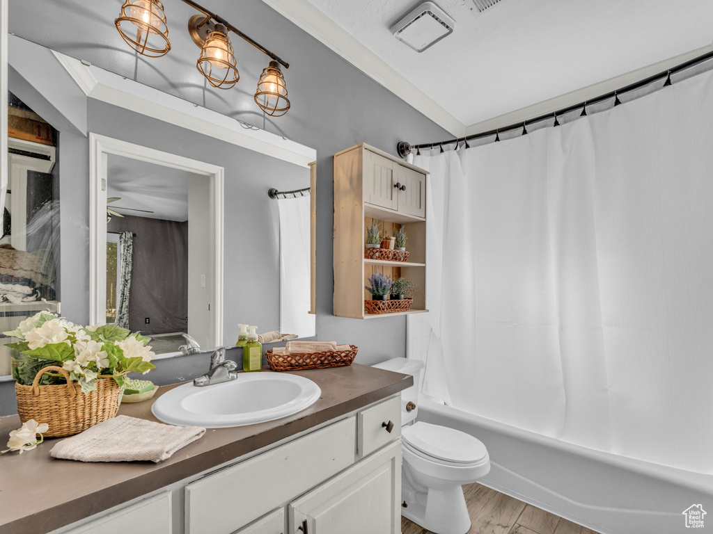 Full bath featuring vanity, toilet, wood finished floors, and shower / bath combo