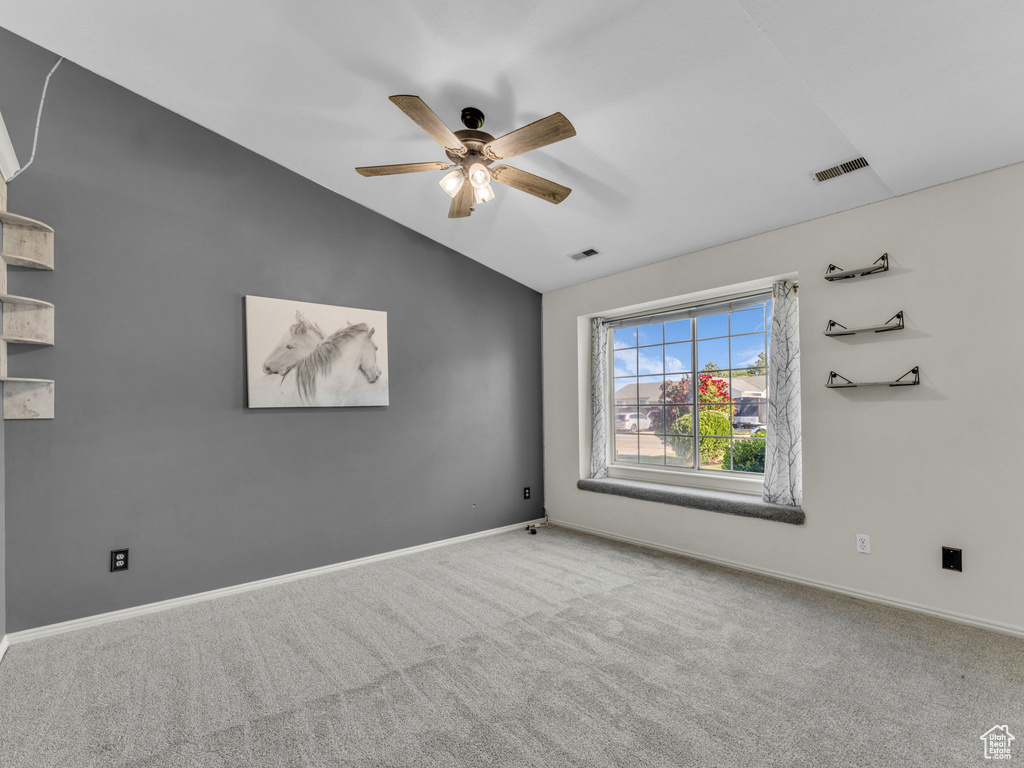 Empty room featuring lofted ceiling, carpet, ceiling fan, and baseboards