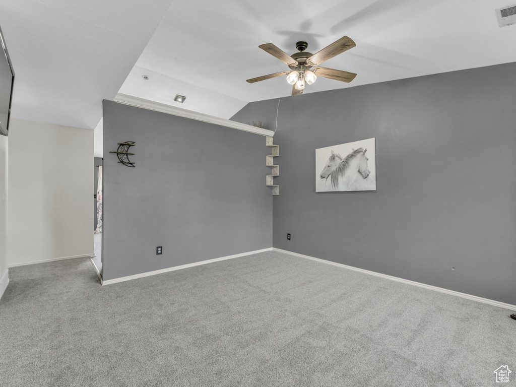 Spare room with a ceiling fan, carpet floors, baseboards, and lofted ceiling