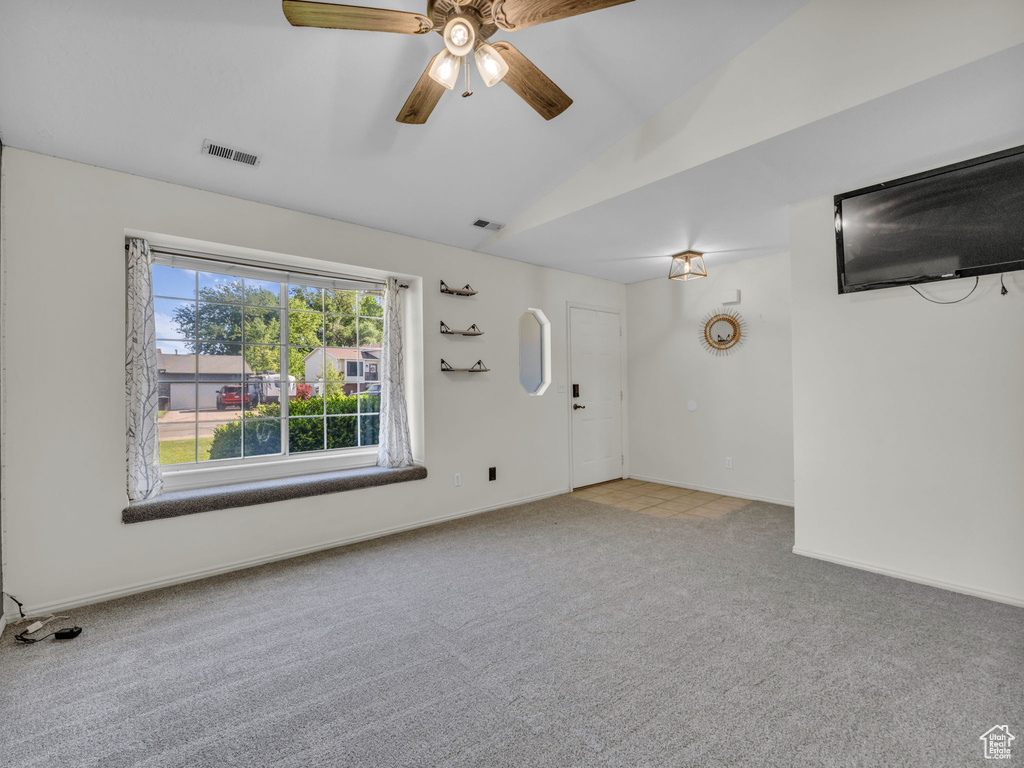 Unfurnished living room with lofted ceiling, carpet floors, a ceiling fan, and baseboards