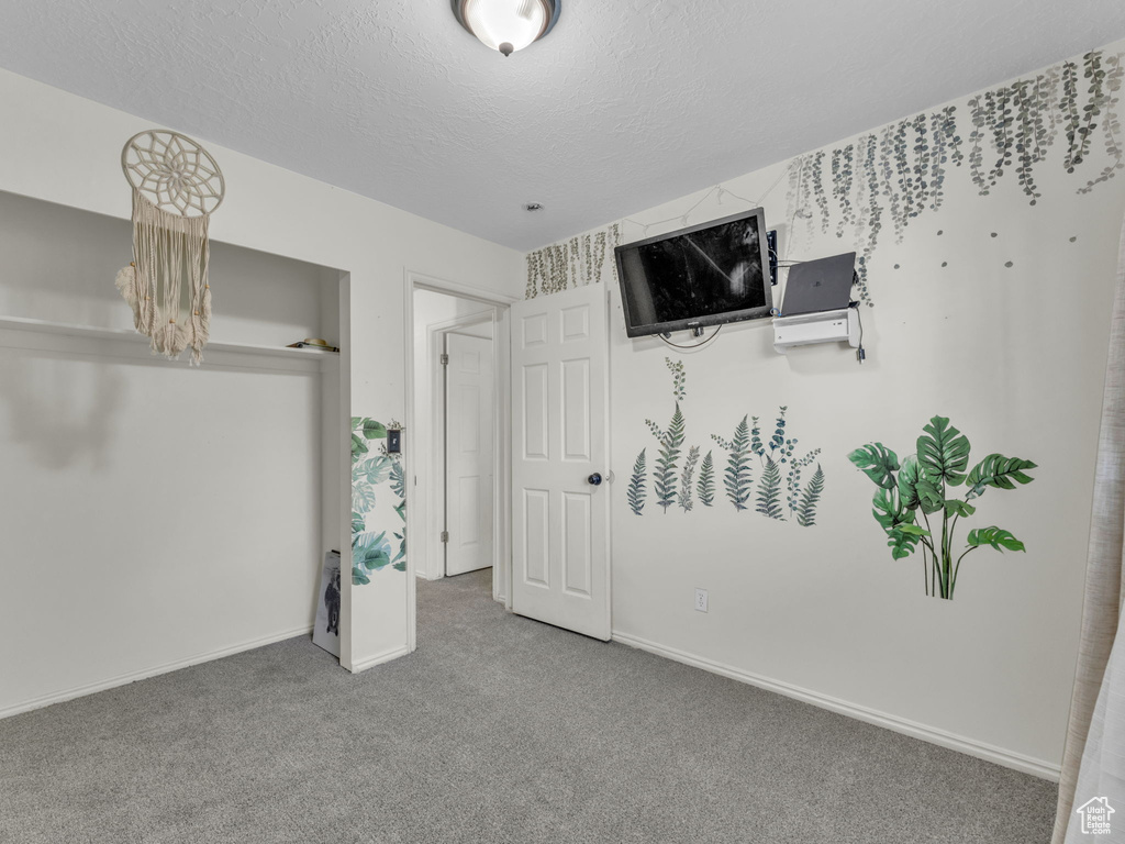 Unfurnished bedroom featuring carpet floors, a textured ceiling, and baseboards