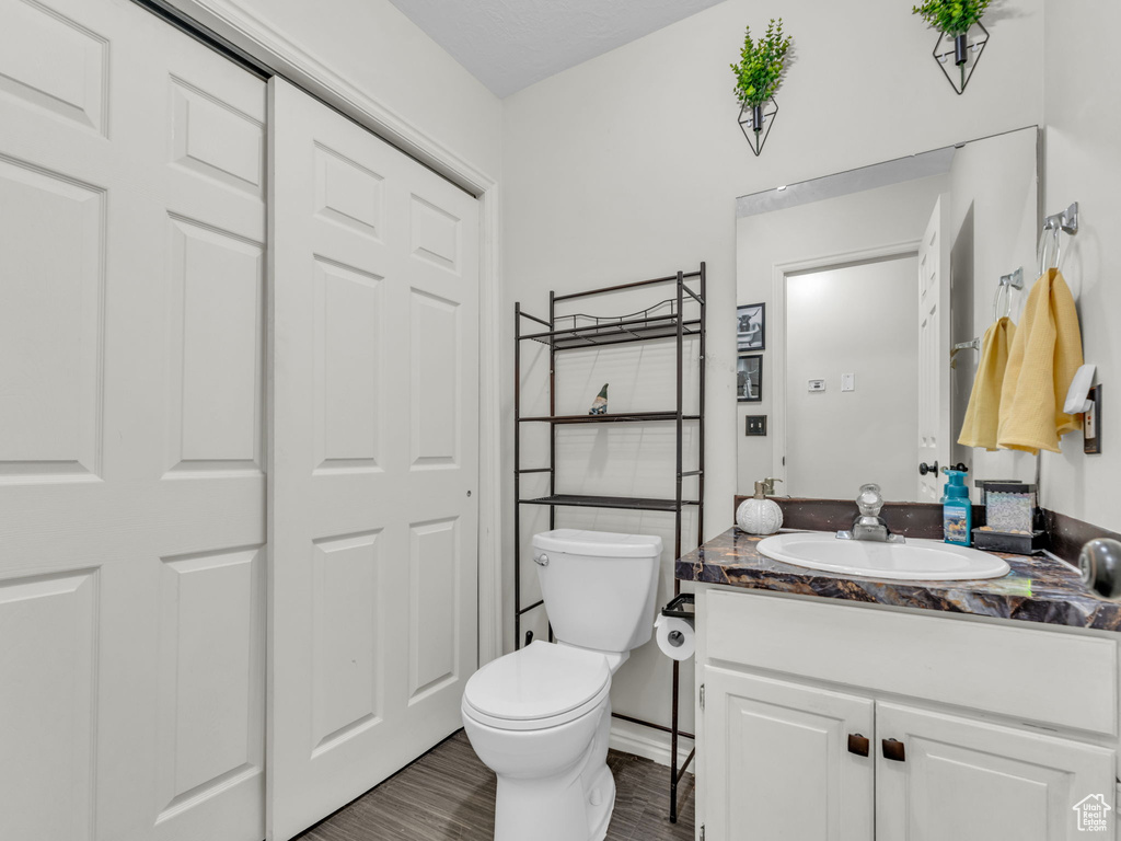Half bathroom with vanity, toilet, and wood finished floors