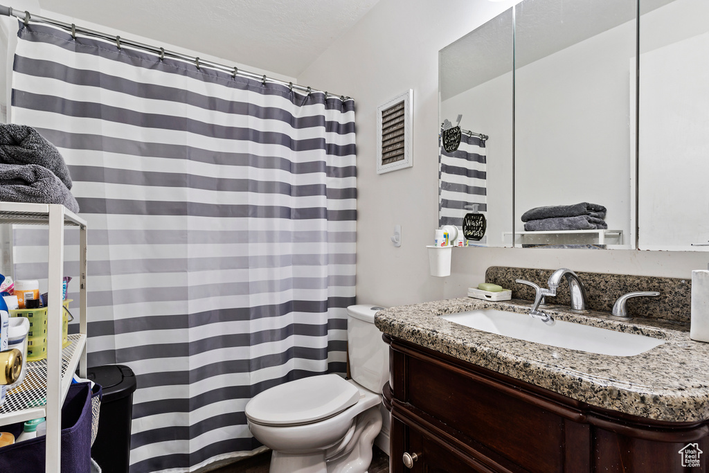 Bathroom featuring toilet, vanity, a shower with shower curtain, and visible vents