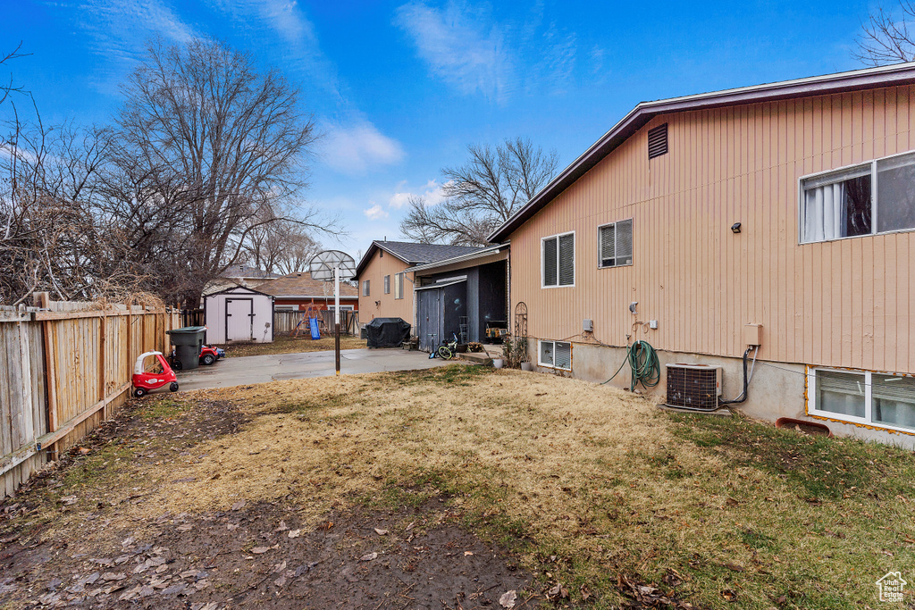 Back of property with a patio, a fenced backyard, a lawn, an outbuilding, and a shed