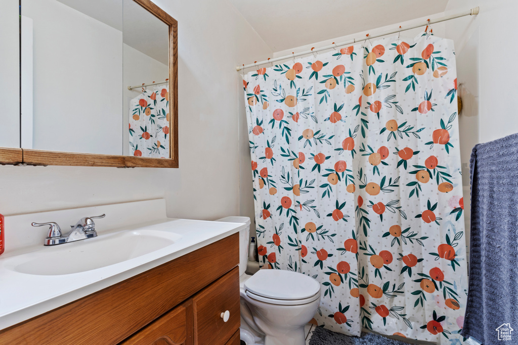 Bathroom featuring a shower with curtain, toilet, and vanity
