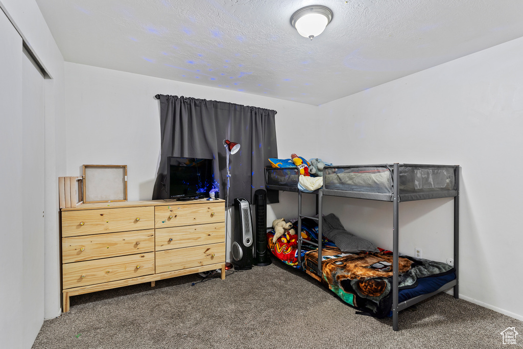 Carpeted bedroom with baseboards and a textured ceiling