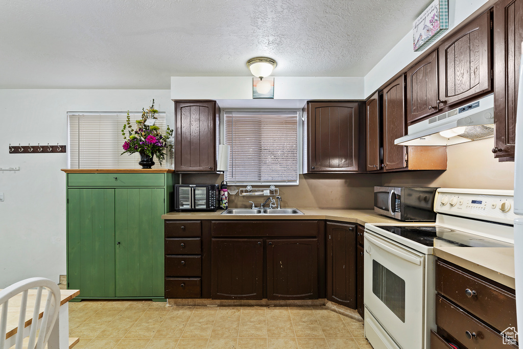 Kitchen featuring light countertops, stainless steel microwave, white electric range oven, under cabinet range hood, and a sink