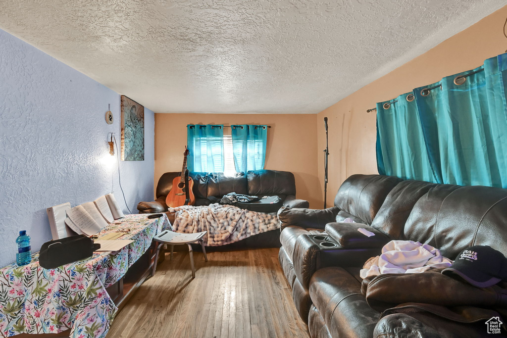 Living room with a textured ceiling, a textured wall, and hardwood / wood-style floors
