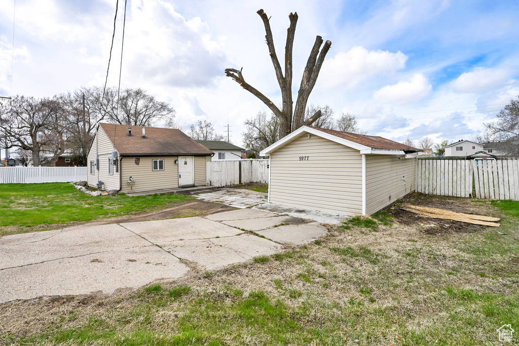 Rear view of house with a patio, an outbuilding, a fenced backyard, and a yard