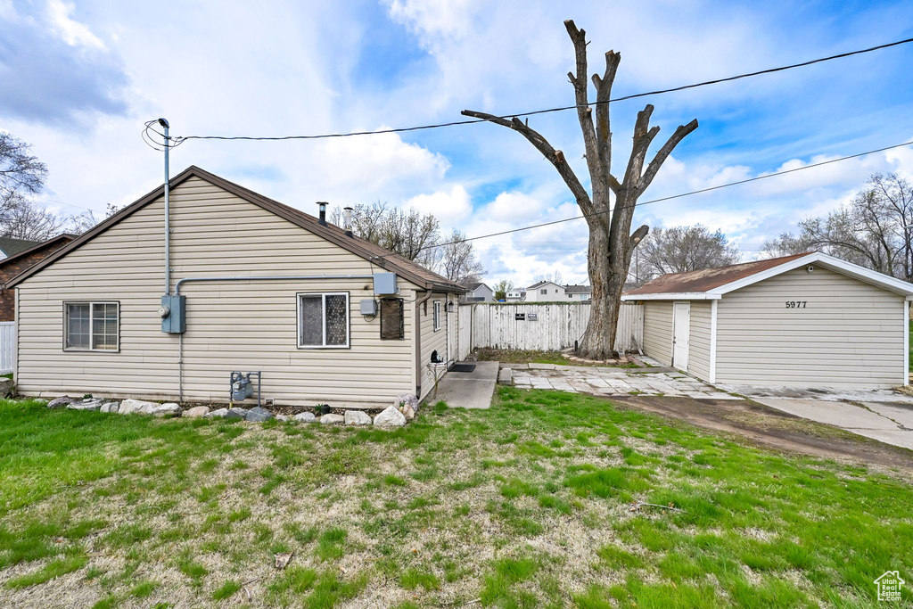 View of property exterior with an outbuilding, a lawn, fence, and a patio area