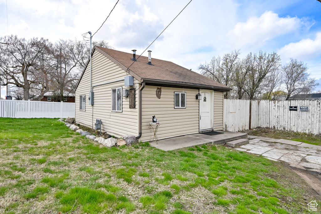 Rear view of house with a fenced backyard, a lawn, a patio area, and roof with shingles