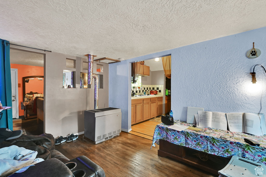 Bedroom featuring light wood-style flooring, a textured wall, fridge, and a textured ceiling