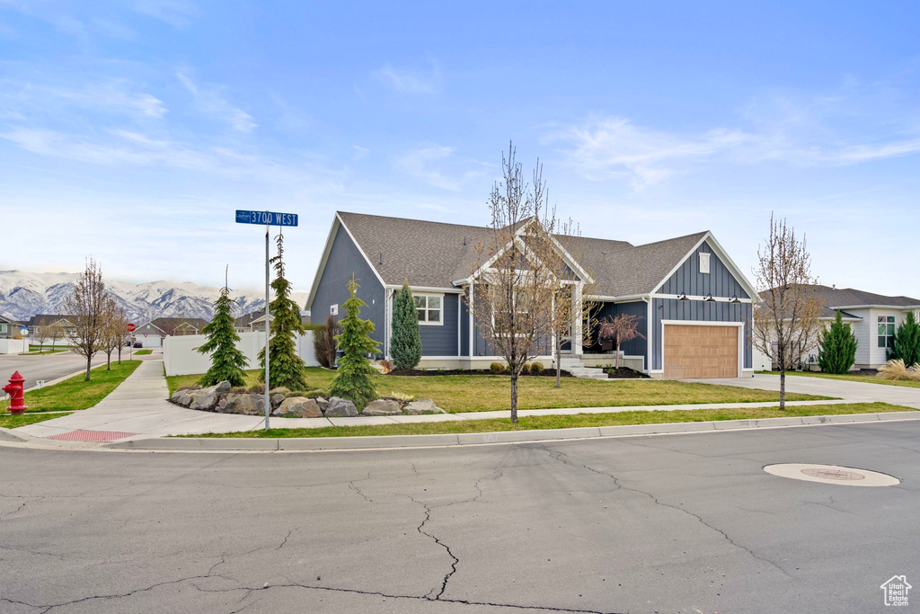 View of front facade featuring driveway, an attached garage, board and batten siding, and a front yard