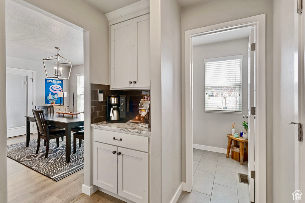 Kitchen featuring baseboards, visible vents, white cabinets, and decorative backsplash