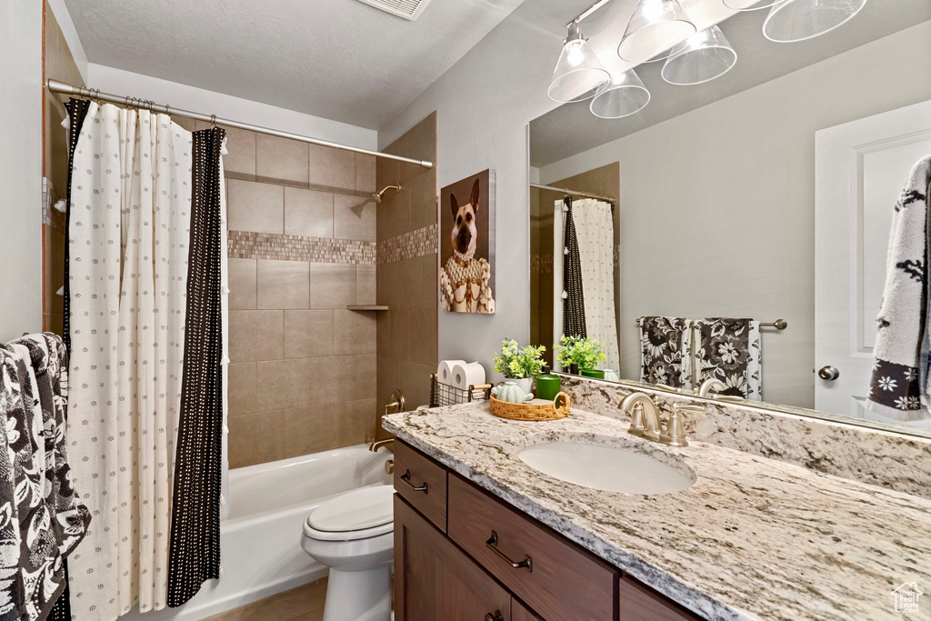 Bathroom with toilet, shower / tub combo with curtain, and vanity