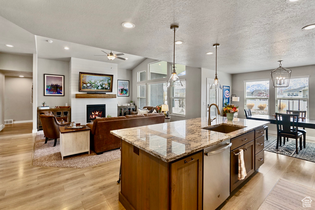 Kitchen featuring stainless steel dishwasher, a fireplace, light wood-type flooring, and a sink