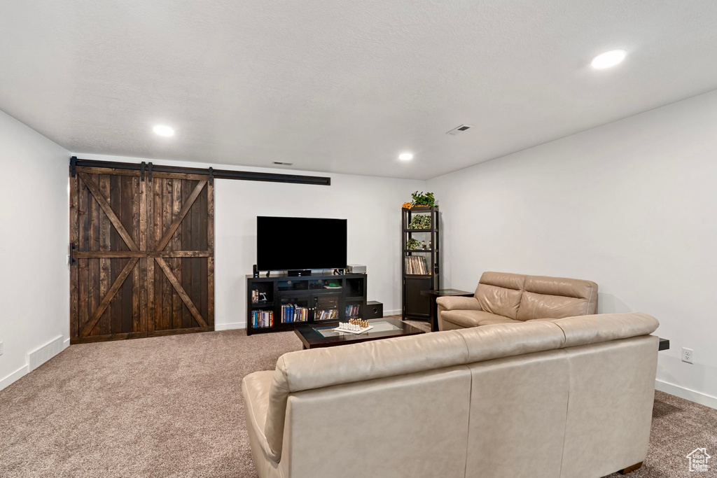 Living room with recessed lighting, visible vents, a barn door, and carpet flooring