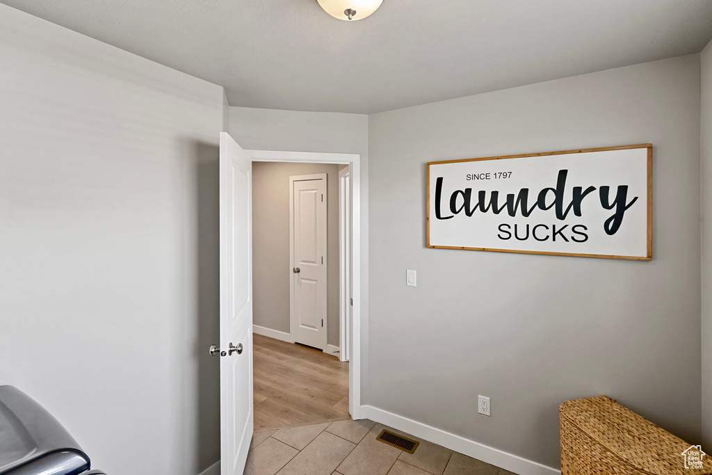 Hall featuring baseboards, visible vents, and light tile patterned floors