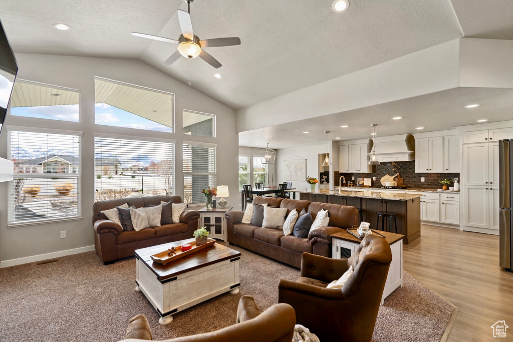 Living room featuring recessed lighting, high vaulted ceiling, baseboards, light wood-style floors, and ceiling fan