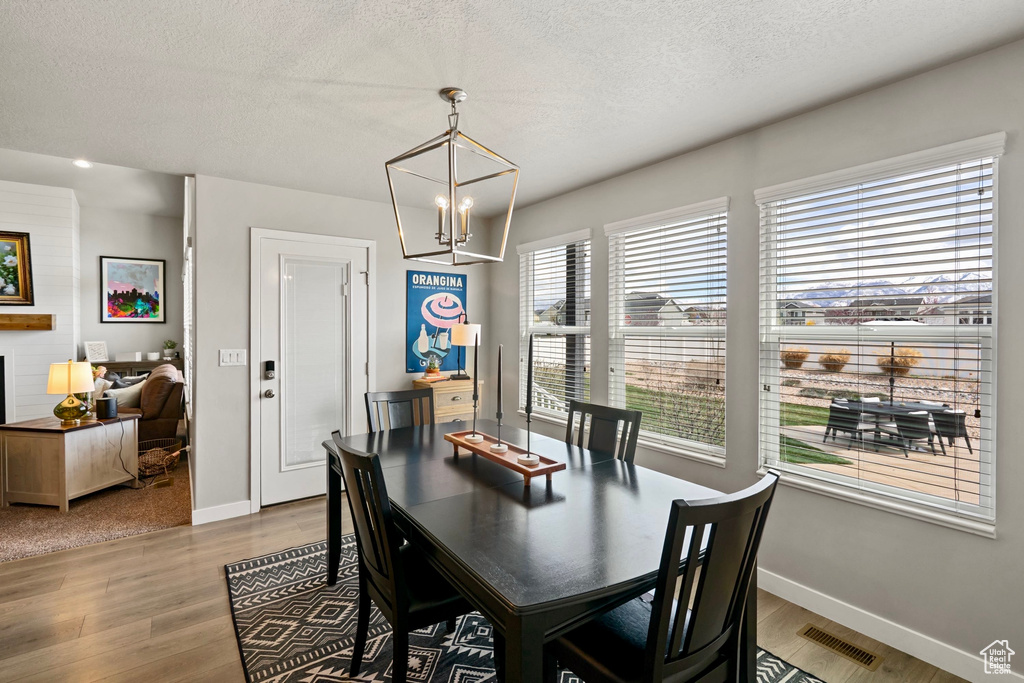 Dining room featuring an inviting chandelier, wood finished floors, a textured ceiling, and visible vents